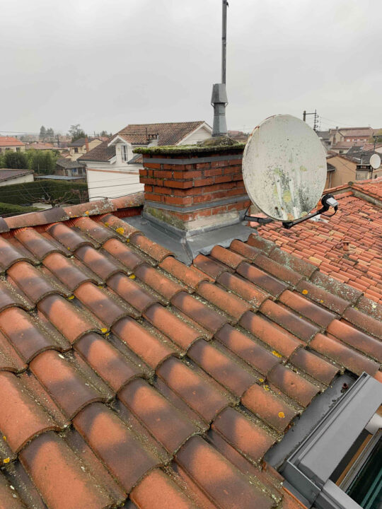 **Balise alt :** Toit en tuiles avec cheminée et parabole à Toulouse, région Occitanie.