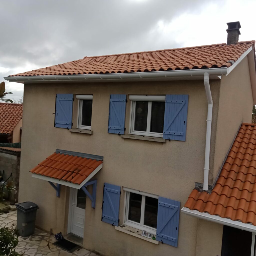 Maison rénovée avec volets bleus et toiture en tuiles, située à Toulouse.