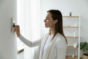 Femme ajustant thermostat; rénovation énergétique; Advalidem; audit énergétique