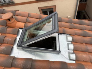 Fenêtre de toit ouverte sur un toit en tuiles, rénovation énergétique AD VALIDEM.