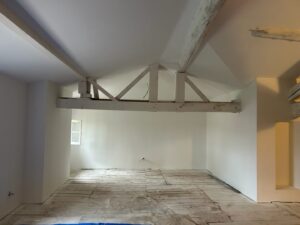 Intérieur en rénovation énergétique par AD VALIDEM, murs et poutres visibles.