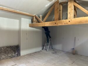Travailleur en rénovation énergétique sous une structure en bois, AD VALIDEM.
